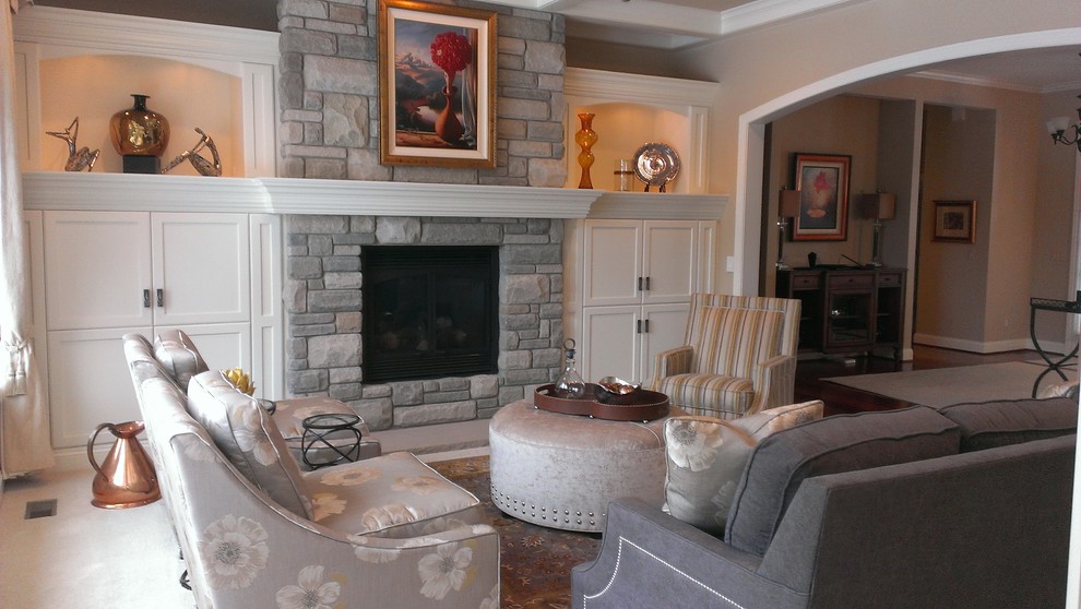 На фото: открытая гостиная комната в классическом стиле с бежевыми стенами, ковровым покрытием, стандартным камином, фасадом камина из камня и скрытым телевизором