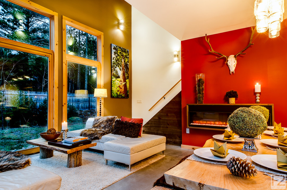На фото: парадная, двухуровневая гостиная комната среднего размера в стиле рустика с красными стенами, бетонным полом, подвесным камином и серым полом без телевизора