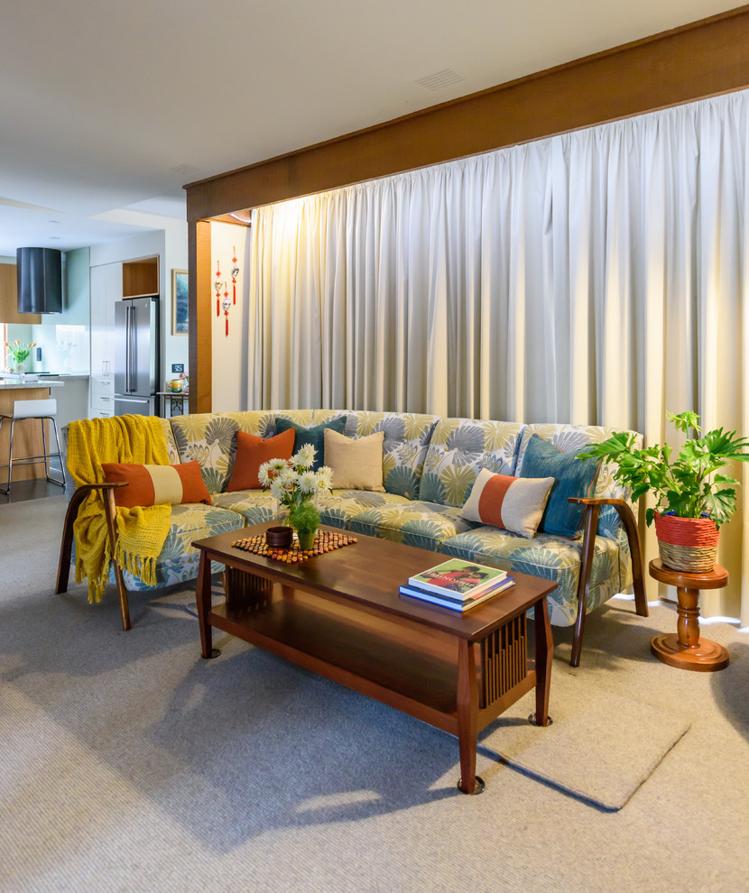 Immagine di un soggiorno minimal di medie dimensioni e aperto con pareti beige, moquette, stufa a legna, cornice del camino in cemento e TV autoportante