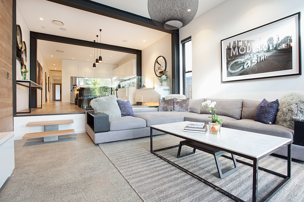 Стильный дизайн: открытая гостиная комната среднего размера в современном стиле с белыми стенами, бетонным полом, телевизором на стене и серым полом - последний тренд