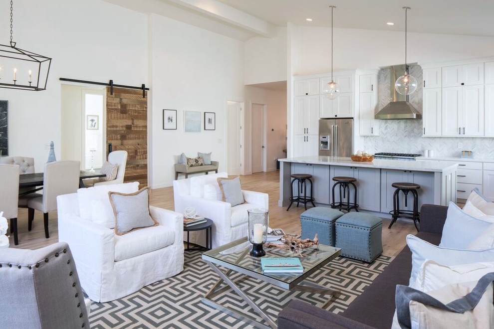 Large farmhouse open plan living room in Los Angeles with white walls, light hardwood flooring and a wall mounted tv.