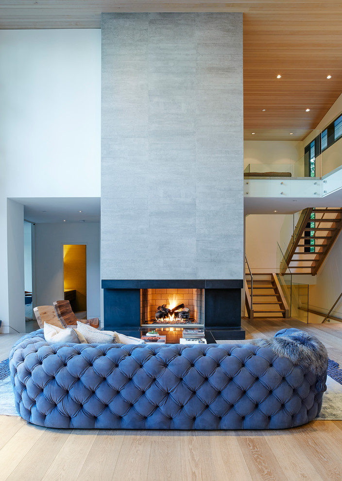 Idée de décoration pour un salon mansardé ou avec mezzanine design de taille moyenne avec un mur blanc, un sol en bois brun, une cheminée standard, un manteau de cheminée en béton et aucun téléviseur.