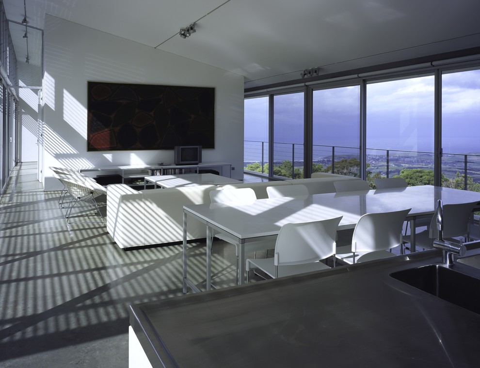 Cette image montre un grand salon minimaliste ouvert avec sol en béton ciré, un mur blanc et un téléviseur fixé au mur.