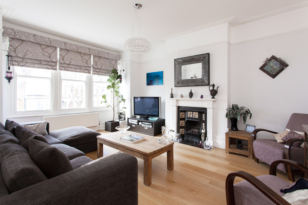 Imagen de salón nórdico con paredes blancas, suelo de madera clara, todas las chimeneas y televisor independiente