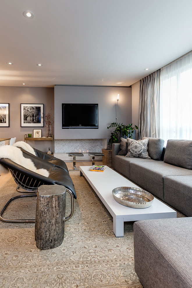 Immagine di un soggiorno chic di medie dimensioni e aperto con pareti grigie, parquet chiaro, camino lineare Ribbon, cornice del camino piastrellata e TV a parete