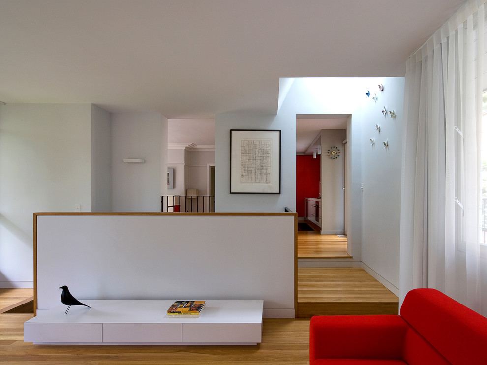 Modelo de salón contemporáneo con paredes blancas, suelo de madera en tonos medios y cortinas