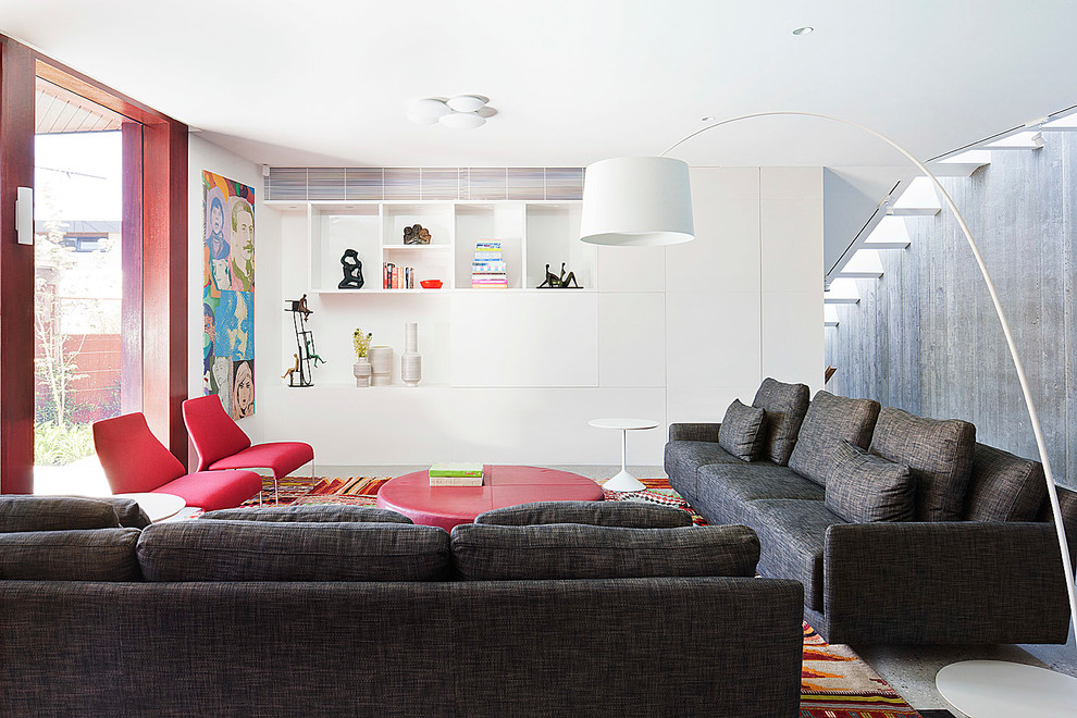 Cette image montre un grand salon design ouvert avec sol en béton ciré, un téléviseur dissimulé, une salle de réception et un mur blanc.