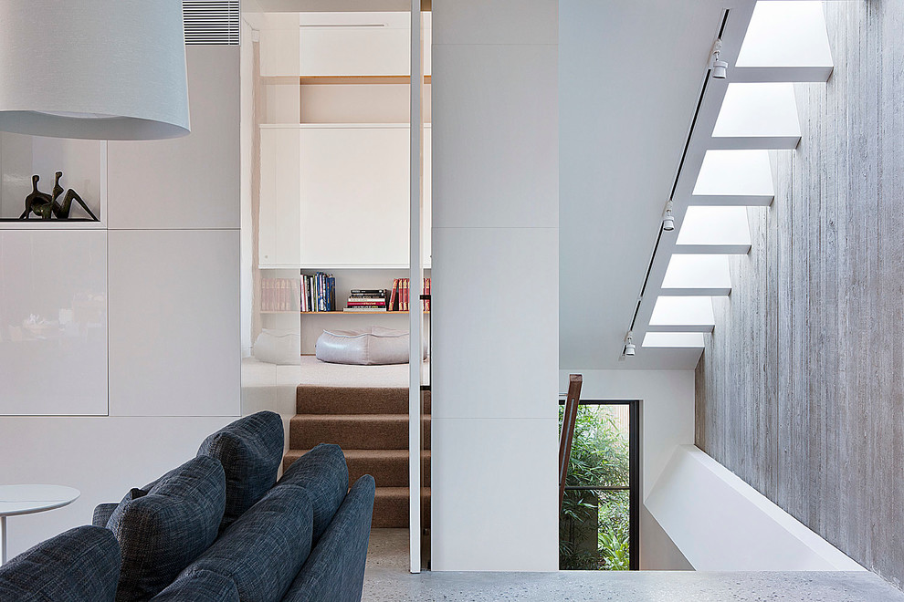 Immagine di un grande soggiorno design aperto con pareti bianche, pavimento in cemento e TV nascosta