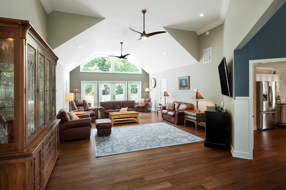 Imagen de salón abierto clásico grande con paredes beige, suelo de madera en tonos medios y televisor colgado en la pared