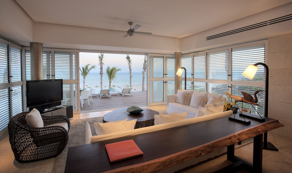 Идея дизайна: гостиная комната среднего размера в морском стиле с белыми стенами, полом из известняка и отдельно стоящим телевизором без камина