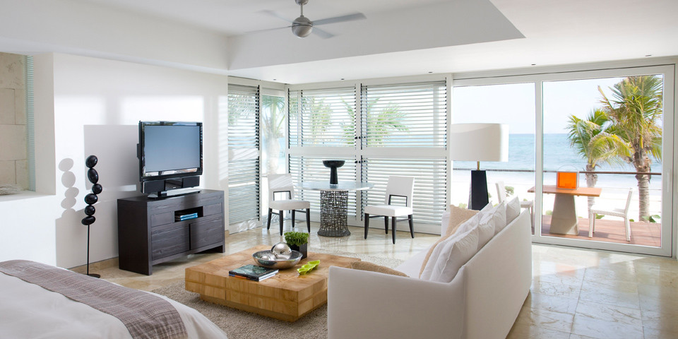 マイアミにある広いコンテンポラリースタイルのおしゃれなリビング (白い壁、暖炉なし、据え置き型テレビ、ライムストーンの床) の写真
