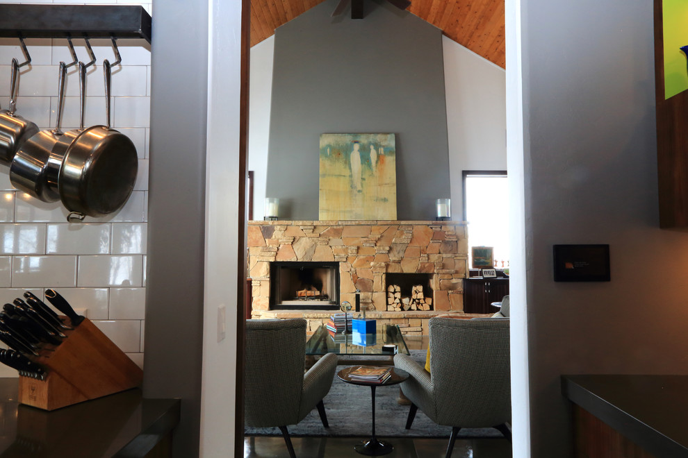 Inspiration pour un grand salon traditionnel ouvert avec un mur gris, sol en béton ciré, une cheminée standard, un manteau de cheminée en pierre et aucun téléviseur.