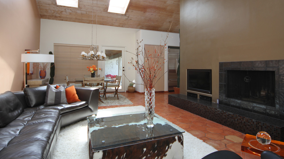 Пример оригинального дизайна: большая парадная, открытая гостиная комната в стиле модернизм с оранжевыми стенами, полом из терракотовой плитки, стандартным камином, фасадом камина из плитки и мультимедийным центром