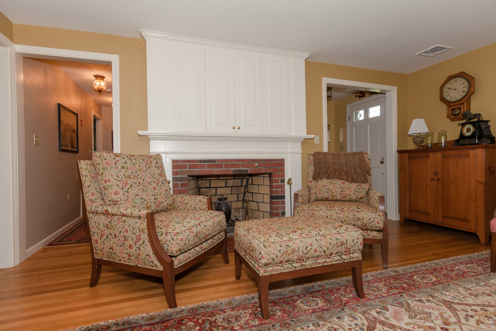 Mittelgroßes, Abgetrenntes Klassisches Wohnzimmer mit beiger Wandfarbe, braunem Holzboden, Kamin, Kaminumrandung aus Backstein und Multimediawand in Boston