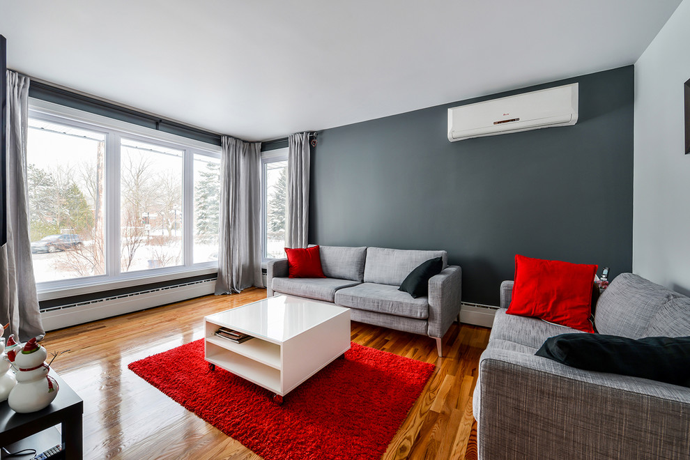Inredning av ett modernt vardagsrum, med grå väggar, mellanmörkt trägolv och en väggmonterad TV
