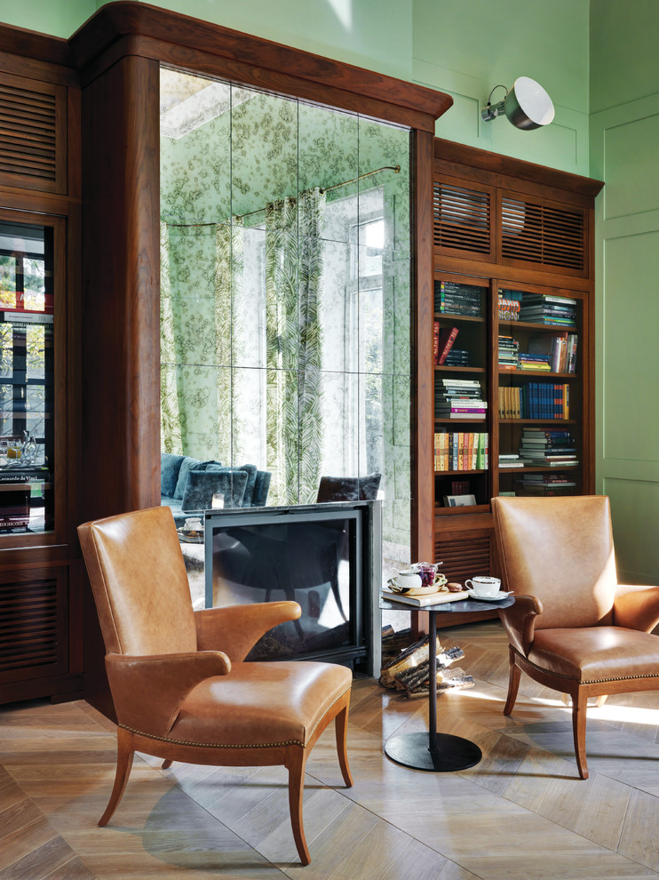 Idee per un soggiorno tradizionale con libreria, pareti verdi, pavimento in legno massello medio e camino classico