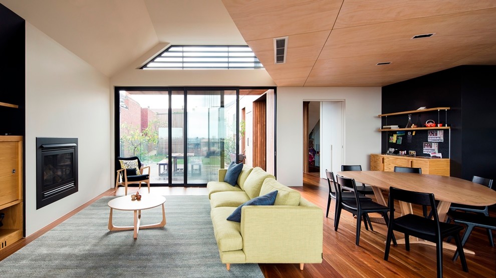 Immagine di un soggiorno design di medie dimensioni e aperto con pareti bianche, pavimento in legno massello medio e camino classico