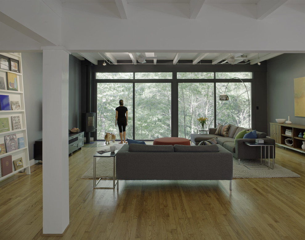 Свежая идея для дизайна: открытая гостиная комната в современном стиле с светлым паркетным полом и печью-буржуйкой - отличное фото интерьера