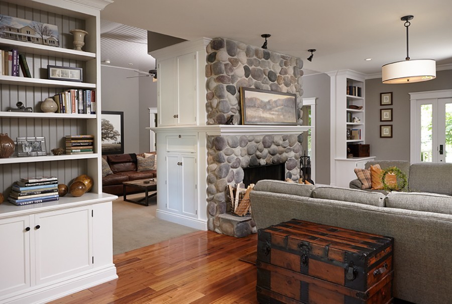 Photo of a rural open plan living room in Grand Rapids with grey walls, medium hardwood flooring, brown floors, a standard fireplace and a stacked stone fireplace surround.