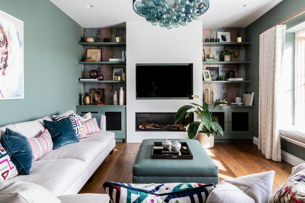 На фото: гостиная комната в современном стиле с зелеными стенами, паркетным полом среднего тона, горизонтальным камином, телевизором на стене и коричневым полом с