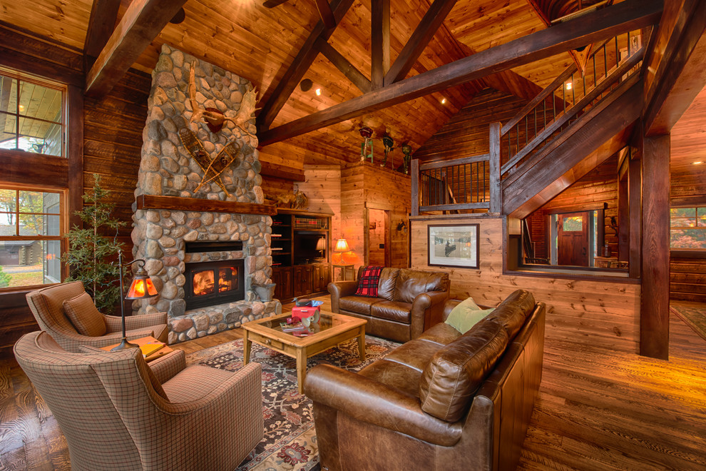 Inspiration for a rustic open plan living room in Minneapolis with brown walls, medium hardwood flooring, a standard fireplace, a stone fireplace surround and a built-in media unit.
