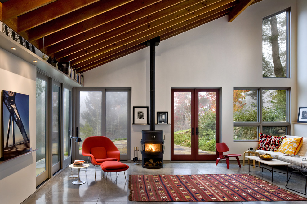 На фото: гостиная комната в современном стиле с бетонным полом и печью-буржуйкой