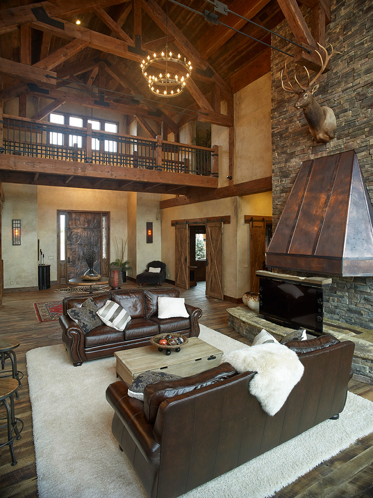 Exemple d'un grand salon montagne ouvert avec un mur beige, parquet foncé, cheminée suspendue, un manteau de cheminée en pierre, une salle de réception et aucun téléviseur.