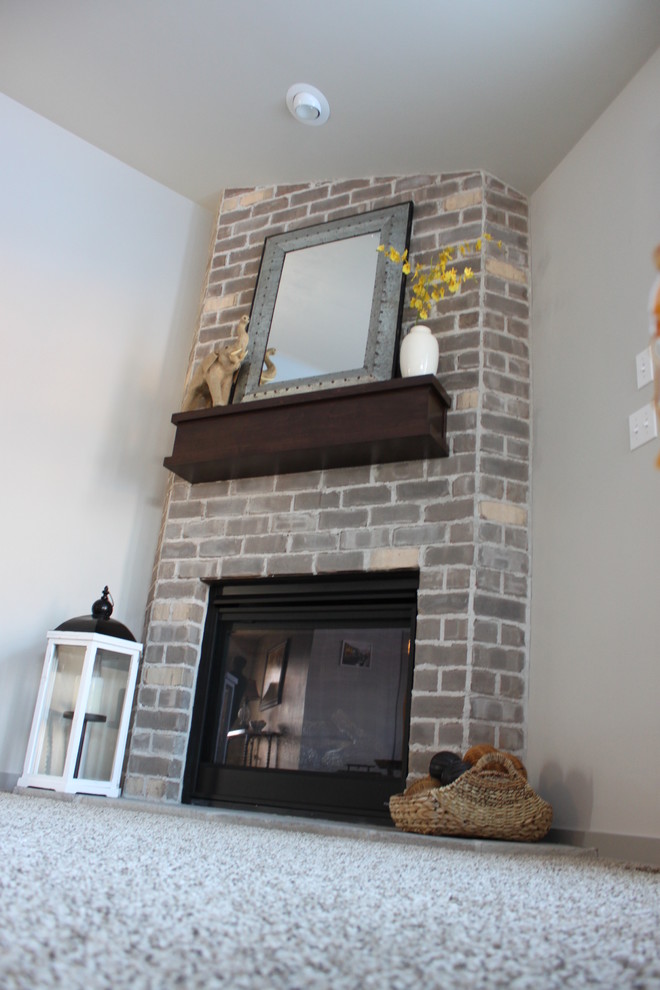На фото: открытая гостиная комната среднего размера в стиле кантри с серыми стенами, ковровым покрытием, угловым камином и фасадом камина из кирпича с