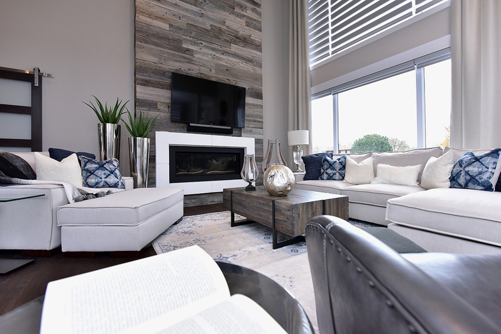 Großes Modernes Wohnzimmer mit Kaminumrandung aus Holz, TV-Wand und braunem Boden in Sonstige