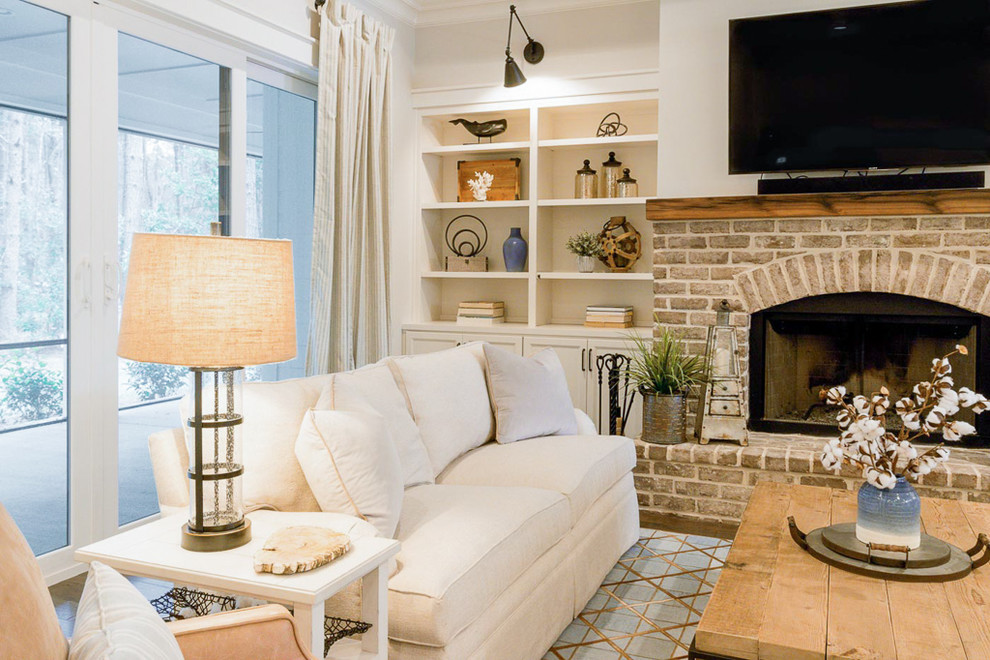 Example of a mid-sized farmhouse open concept dark wood floor and brown floor living room design in Atlanta with white walls, a standard fireplace, a brick fireplace and a wall-mounted tv