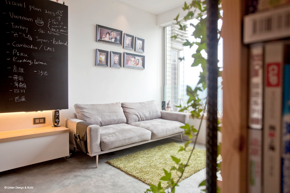 Cette image montre un petit salon mansardé ou avec mezzanine urbain avec un mur blanc, sol en béton ciré et un téléviseur fixé au mur.