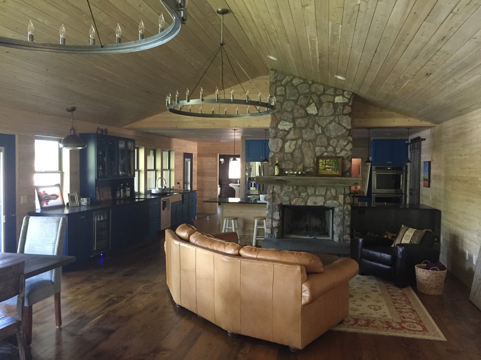 Photo of a large rustic formal open plan living room in Other with brown walls, medium hardwood flooring, a standard fireplace, a stone fireplace surround and no tv.