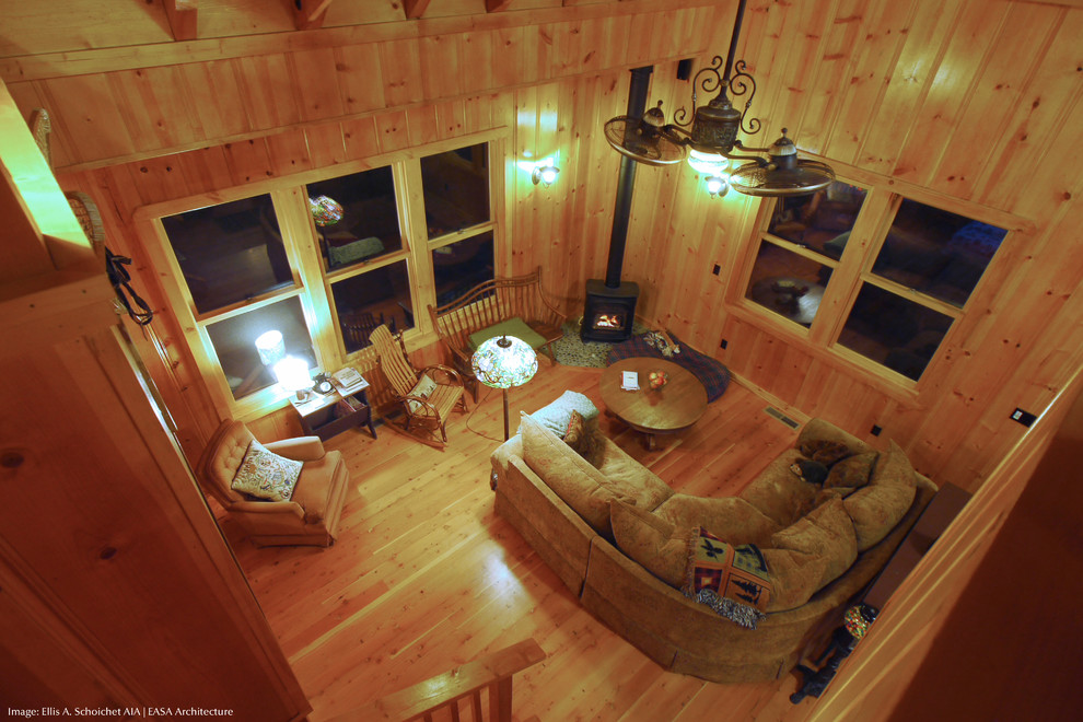 Imagen de salón tipo loft rústico pequeño con paredes marrones, suelo de madera en tonos medios, estufa de leña y suelo marrón
