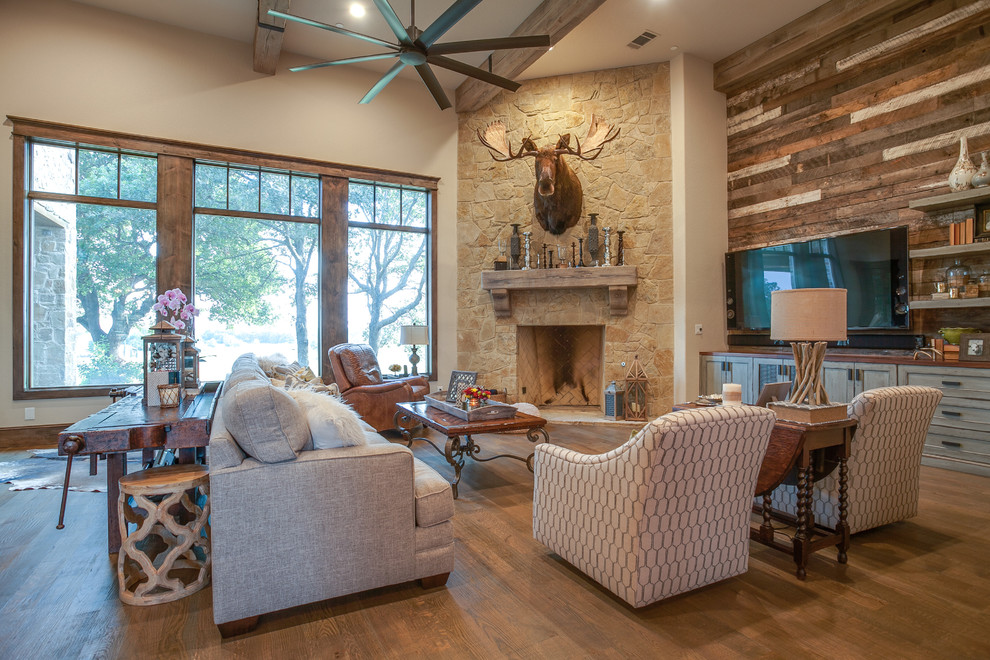 Inspiration for a mid-sized rustic dark wood floor living room remodel in Dallas with beige walls, a standard fireplace, a stone fireplace and a tv stand