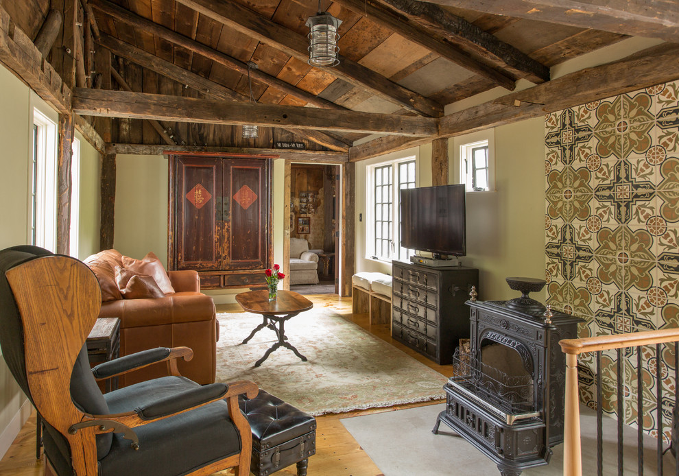 Cette photo montre un grand salon nature avec un mur vert, un sol en bois brun, un poêle à bois et un téléviseur indépendant.