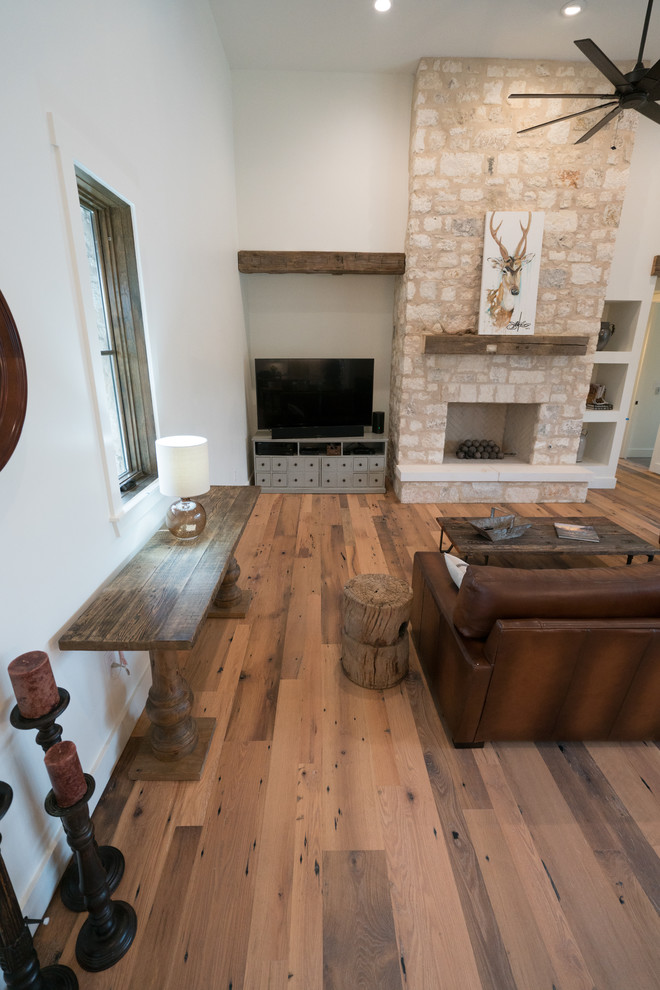 Landhaus Wohnzimmer mit braunem Holzboden und Kaminumrandung aus Stein in Austin