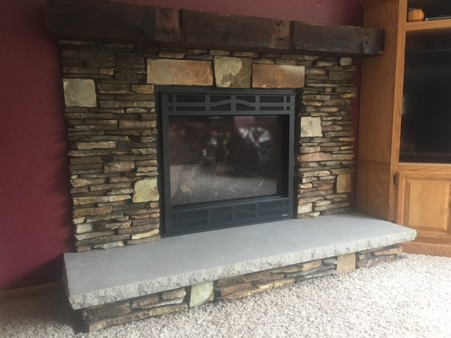 Photo of a medium sized rustic living room in Cedar Rapids with a standard fireplace, a stone fireplace surround, red walls, carpet and beige floors.