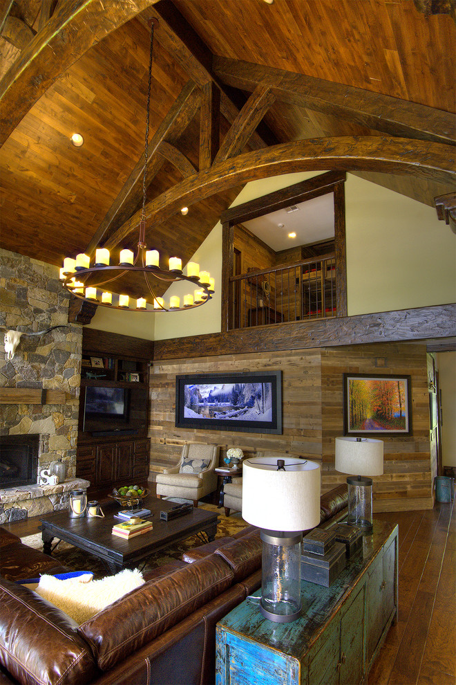 Large mountain style open concept medium tone wood floor and brown floor living room photo in Other with beige walls, a standard fireplace and a stone fireplace