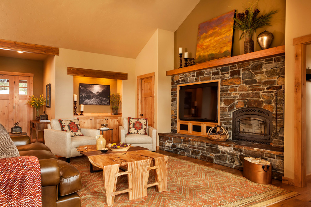 Cette image montre un grand salon chalet ouvert avec un sol en bois brun, une cheminée standard, un manteau de cheminée en bois et un sol marron.