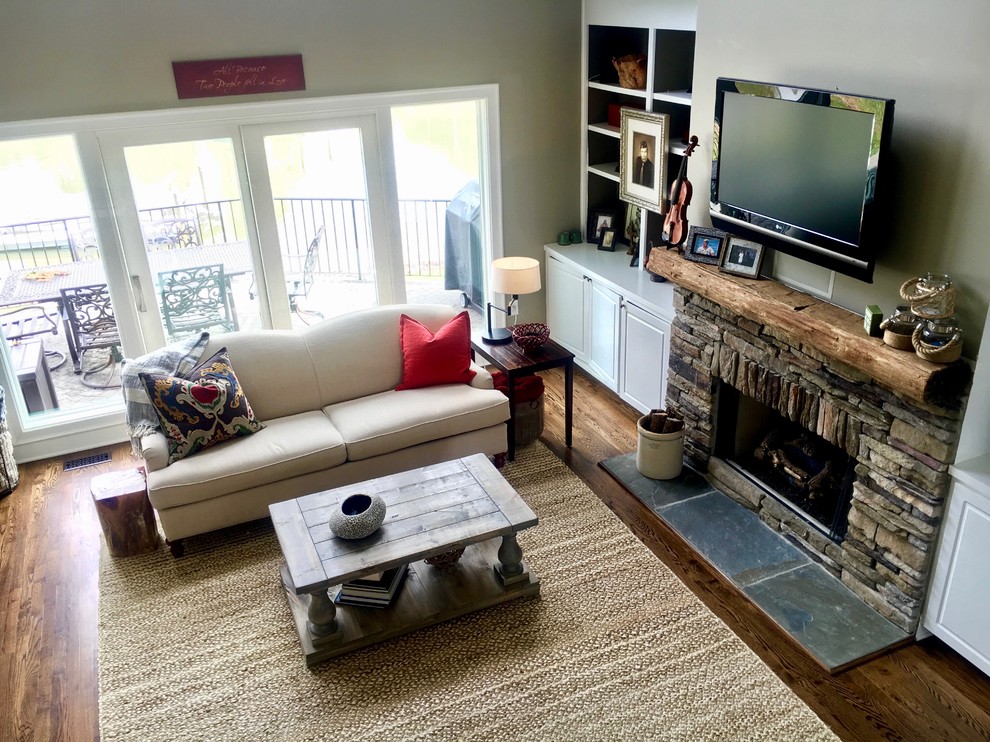シャーロットにある中くらいなラスティックスタイルのおしゃれなLDK (グレーの壁、濃色無垢フローリング、標準型暖炉、石材の暖炉まわり、壁掛け型テレビ、茶色い床) の写真