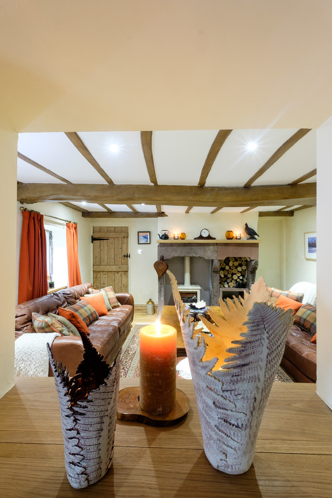 Idée de décoration pour un grand salon chalet fermé avec un mur beige, un sol en bois brun, un poêle à bois et un manteau de cheminée en pierre.