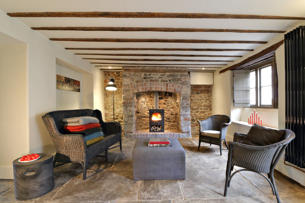 Aménagement d'un petit salon campagne ouvert avec un mur blanc, un poêle à bois, un manteau de cheminée en brique et un sol en calcaire.