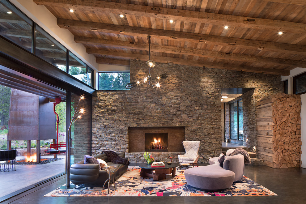 Example of a mountain style open concept concrete floor and gray floor living room design in Other with a standard fireplace