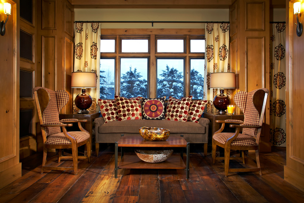 На фото: гостиная комната в стиле рустика с темным паркетным полом и коричневым диваном с