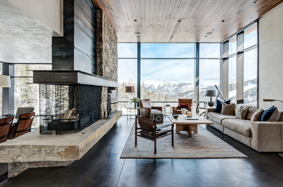 Rustic living room in Other with concrete flooring, a two-sided fireplace and feature lighting.