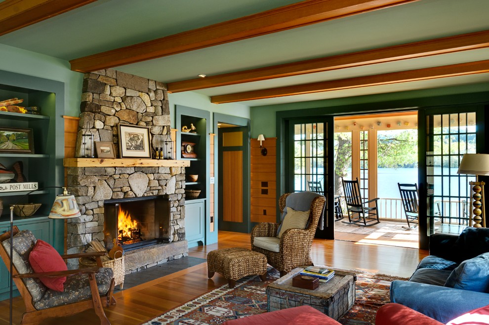 Aménagement d'un salon montagne avec un mur vert, un sol en bois brun, une cheminée standard et un manteau de cheminée en pierre.