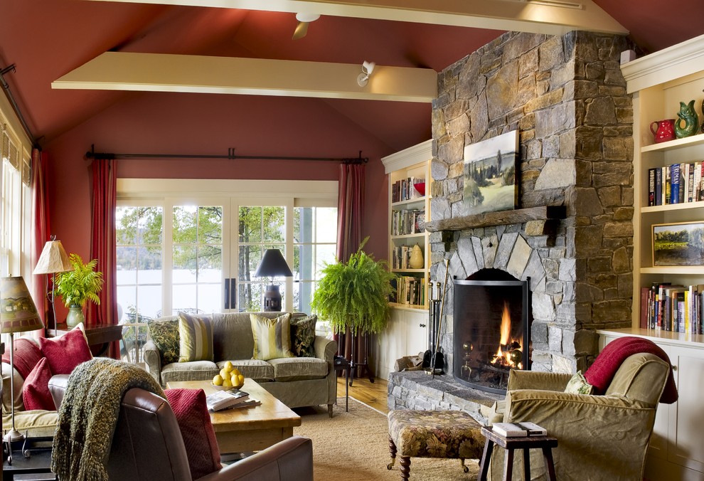 Стильный дизайн: гостиная комната:: освещение в стиле рустика с красными стенами, фасадом камина из камня и ковром на полу - последний тренд