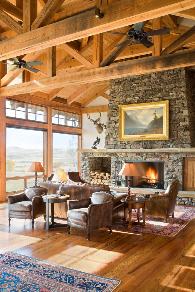 Photo of a medium sized rustic formal open plan living room in Other with white walls, medium hardwood flooring, a standard fireplace, a stone fireplace surround and feature lighting.
