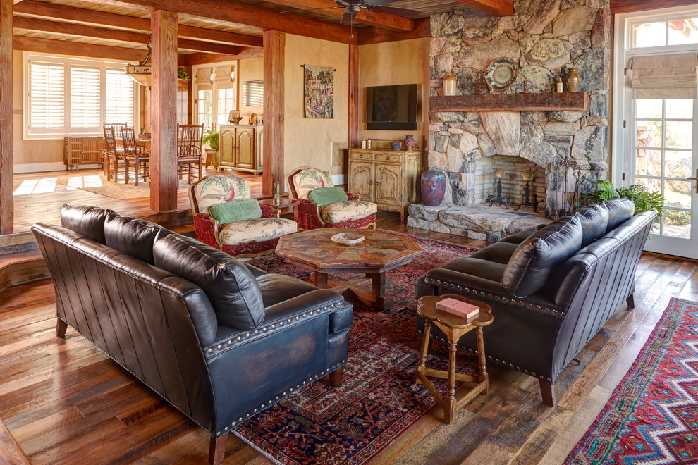 Exempel på ett rustikt vardagsrum, med beige väggar, mellanmörkt trägolv, en standard öppen spis, en spiselkrans i sten och en väggmonterad TV