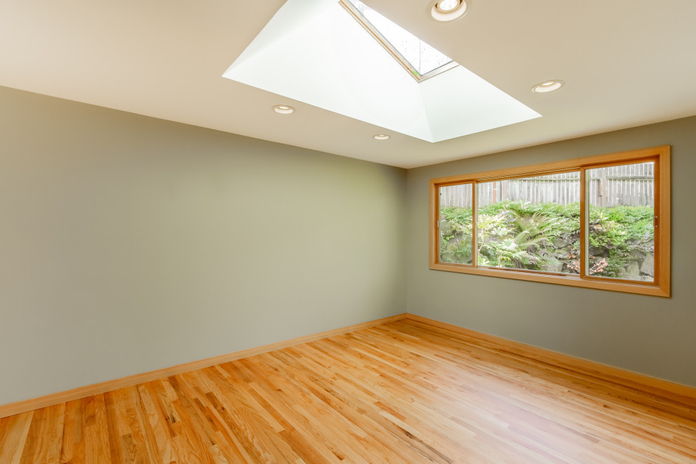 Offenes Modernes Wohnzimmer mit grauer Wandfarbe, braunem Holzboden, Kaminumrandung aus Stein und orangem Boden in Seattle